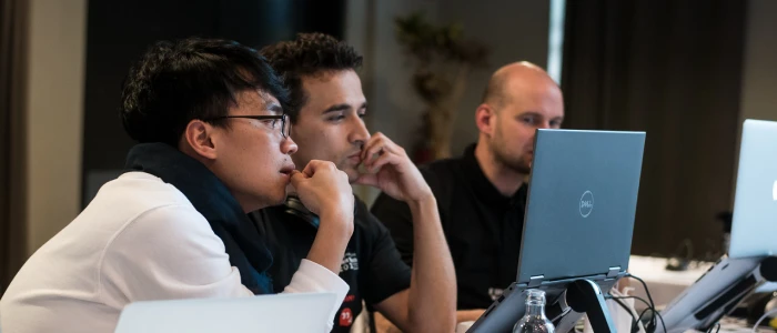 UI Designer vacancy: Two people huddled behind laptop looking at a design